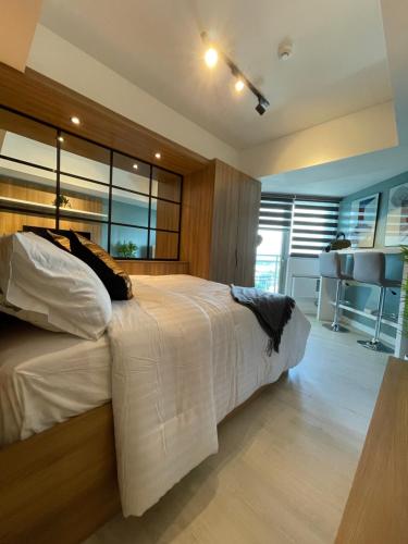 a bedroom with a large white bed and a kitchen at KRYSTL KRIB Azure North in San Fernando