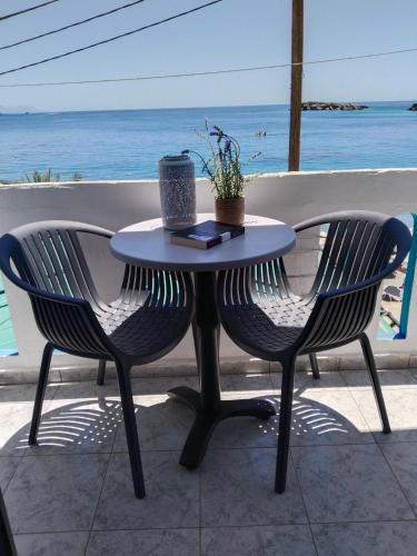 a table and two chairs with the ocean in the background at Notos Rooms in Loutro