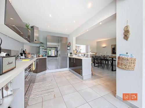 a large kitchen with white appliances and a dining area at L'ensoleillée - Proximité plage in Wimereux