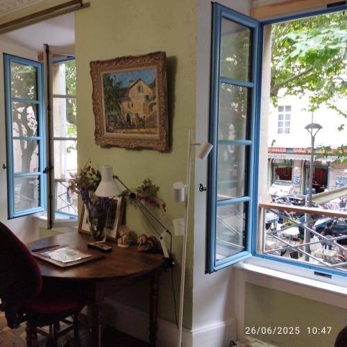 Cette chambre dispose de fenêtres et d'une table avec une lampe. dans l'établissement Grand appartement de charme avec parking privé, à Florac