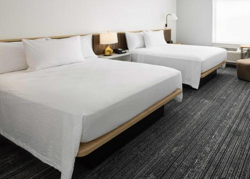 two beds in a hotel room with white sheets at TownePlace Suites by Marriott Plant City in Plant City