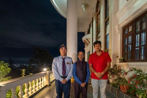 three men standing on a balcony of a building at The White House Villa 8 bedroom with Swimming Pool in Kathmandu