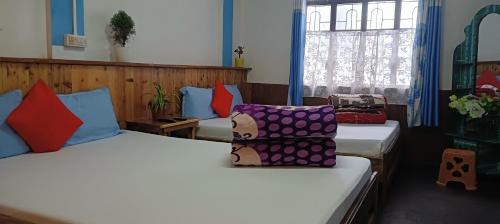 a room with two beds with colorful pillows at Winter Inn Homestay in Lava