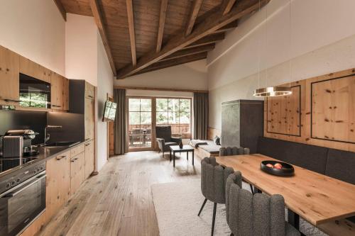 a kitchen and dining room with a wooden table and chairs at Das Kaltenbach - ApartHotel in Kaltenbach