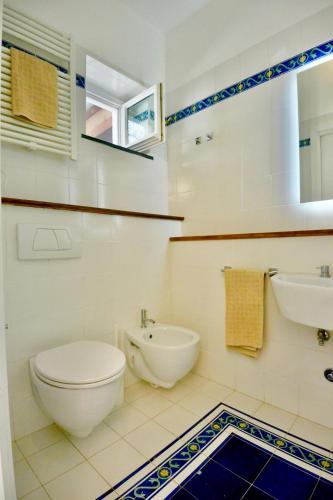 a white bathroom with a toilet and a sink at Cala Prodani Rooms in Savona