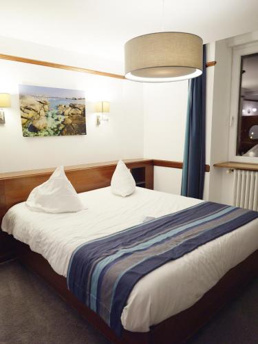 a bedroom with a large bed with a blue curtain at Hôtel des Rochers in Perros-Guirec