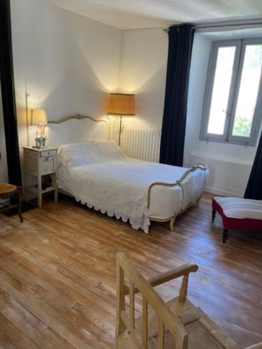 une chambre avec un lit, une chaise et des fenêtres dans l'établissement Grand appartement de charme avec parking privé, à Florac