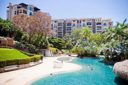 a swimming pool in a resort with people in it at Matapalo Diria #504 Amazing Condo-Ocean View in Tamarindo