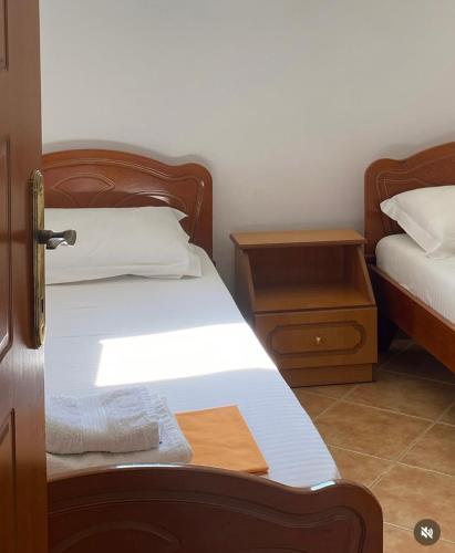 a bedroom with two beds with white sheets and wooden furniture at Dema Guesthouse in Ksamil