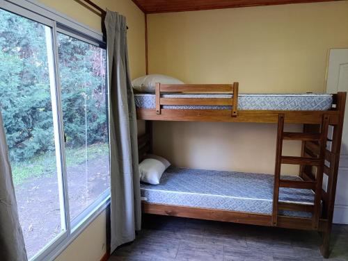 two bunk beds in a room with a window at Cabañas Hamdan villa residencial laguna brava in Balcarce