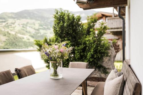a vase of flowers on a table on a balcony at Das Kaltenbach - ApartHotel in Kaltenbach