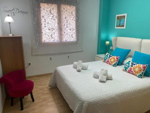 a bedroom with a bed with a red chair and a window at Apartamentos Alcañiz, Ana in Alcañiz