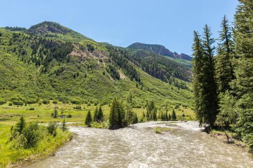 a river in a valley with mountains at Three Sisters Peak Cabin at Filoha Meadows in Redstone