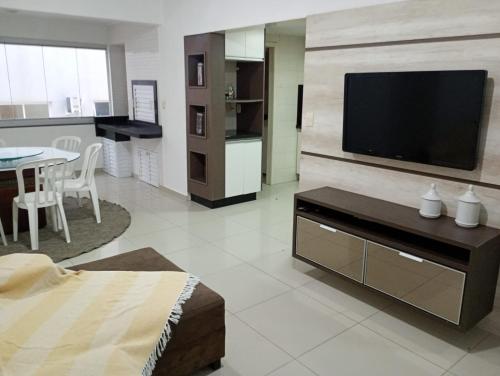 Una sala de estar con un televisor de pantalla plana en una pared. en Apartamento Quadra Mar Meia Praia, en Itapema