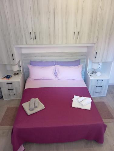 a bedroom with a large bed with purple sheets and shoes at Civico 28 in Badesi