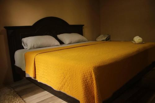a bedroom with a bed with a yellow blanket at Cabaa Luculuc Garden Forest in San Pedro