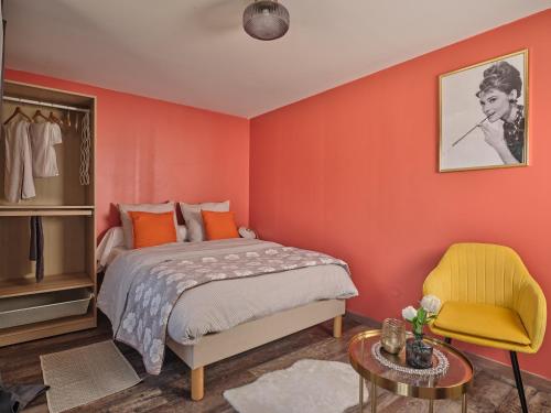1 dormitorio con paredes de color naranja, 1 cama y 1 silla en La Résidence AKWABA, en Saint-Philbert-de-Grand-Lieu