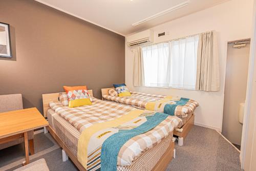 two beds in a room with a table at 8 min walk to JR Chuo Sobu Line Station Ground Floor Room 13 min to Tokyo Direct Train to Asakusa Shinjuku Ueno Akihabara 22sqm in Tokyo