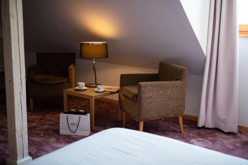 a room with two chairs and a table and a lamp at Hôtel Le Rapp in Colmar