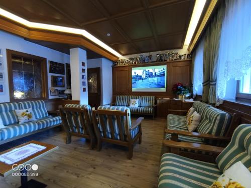 a living room with couches and a flat screen tv at Park Hotel Arnica in Falcade