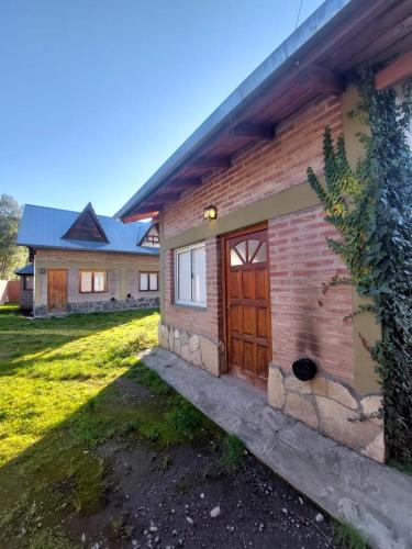 una casa con una puerta de madera en un patio en Paseo Iñaki, en Lago Puelo