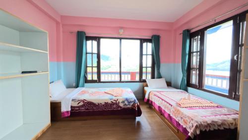 two beds in a room with pink and blue walls at Sadhana Yoga Retreat in Pokhara