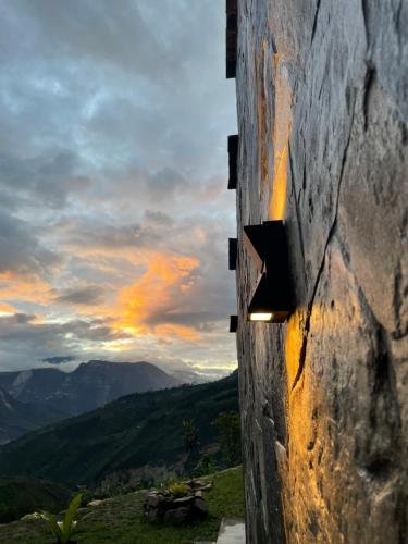 a view from the side of a stone wall with a sunset at La Casa de Mario - Gocta in Cocachimba