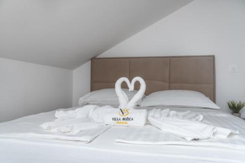 a white swan decoration on a bed with white sheets at Villa Božica - sea view stone villa with free parking in Makarska