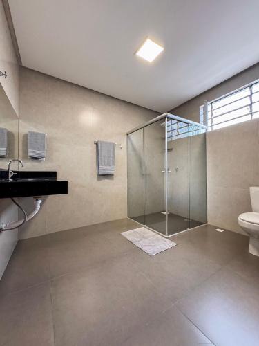 a bathroom with a glass shower and a toilet at Menezes Flat in Rio Verde