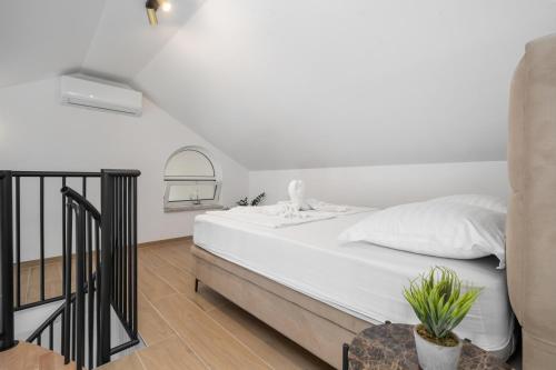 a bedroom with a white bed and a staircase at Villa Božica - sea view stone villa with free parking in Makarska