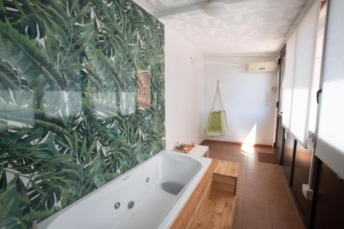 a bathroom with a tub and a green leaf wallpaper at Vista Mare 16 in Siracusa