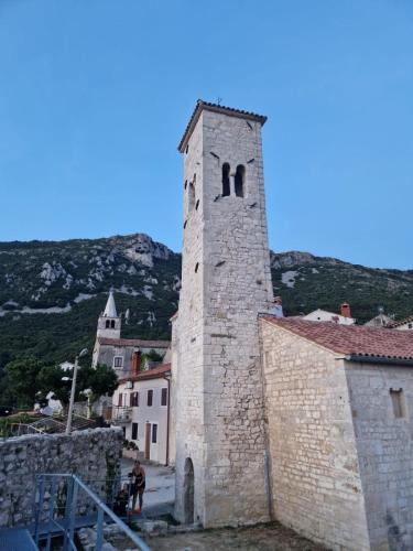 a building with a tower with a mountain in the background at Apartman Fonovici in Juraši