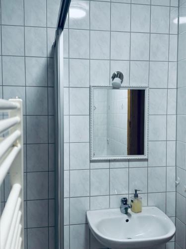 a white tiled bathroom with a sink and a mirror at Siegener Balkon-Refugium in Plauen