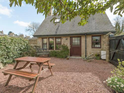 a wooden picnic table in front of a house at Stable Cottage in Alnwick