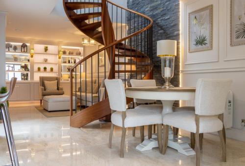 a dining room with a table and chairs and a spiral staircase at GuestReady – Ranelagh Retreat with Urban Access in Dublin