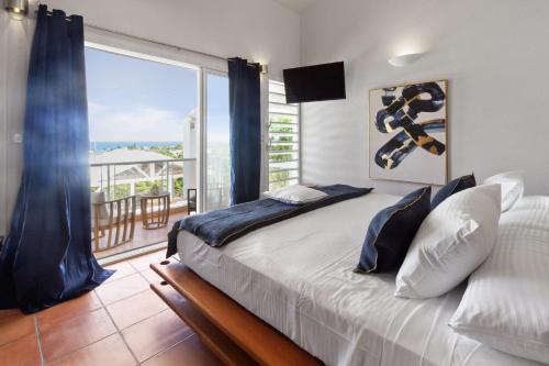 a bedroom with a large bed and a balcony at Villa Maravistah in Saint-François