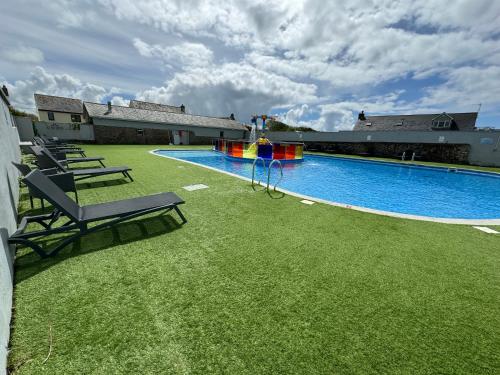 una gran piscina con un parque infantil en un patio en Harrogate Lodge, Bude, en Poughill