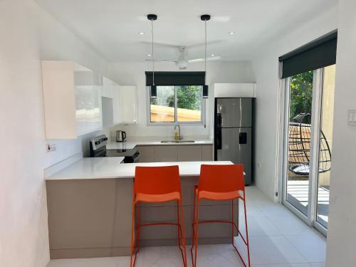 a kitchen with two orange chairs at a counter at The Indianna Luxury Pool & Spa in Whitehouse