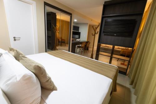 a bedroom with a large white bed and a television at Mais Hotel Aeroporto Salvador in Lauro de Freitas
