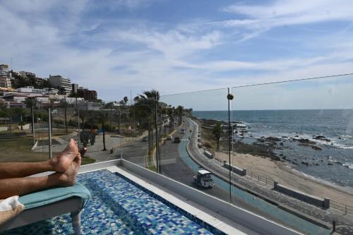 a person sitting on a balcony looking out at the ocean at Malecón de Mazatlan Vista al mar Alberca Infinity Jacuzzi Gym in Mazatlán