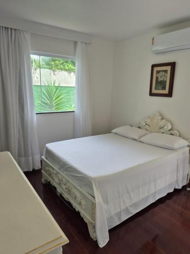 a bedroom with a large white bed with a window at MF Flat in Ilhéus