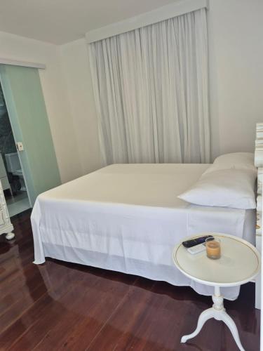 a bedroom with a white bed and a table at MF Flat in Ilhéus