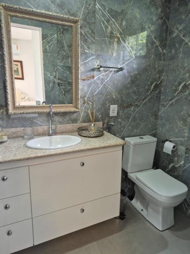 a bathroom with a sink and a toilet and a mirror at MF Flat in Ilhéus