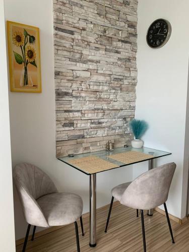 a table with two chairs and a clock on a wall at Chic & Cozy Beige Studio in Bratislava