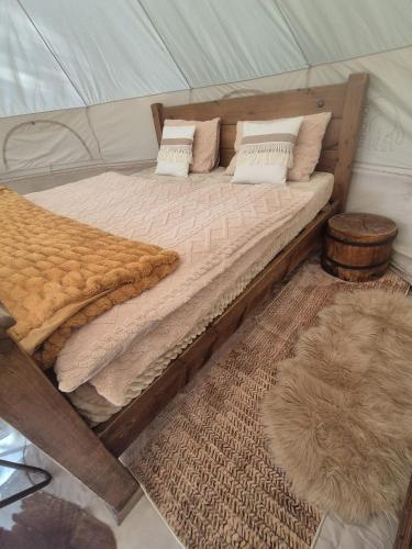 a large wooden bed in a tent with pillows at Šepot in Štôla