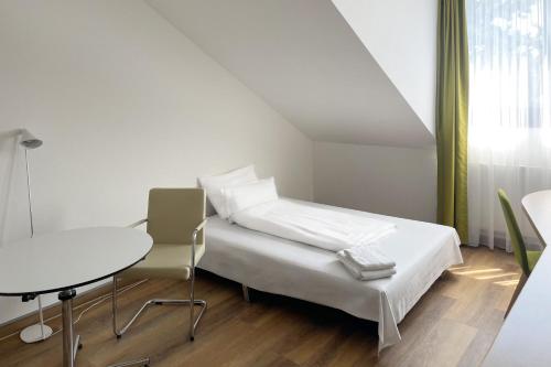 a white bedroom with a bed and a table at Garner Hotel Erlangen Süd by IHG in Erlangen