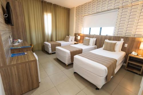 a hotel room with two beds and a television at Mais Hotel Aeroporto Salvador in Lauro de Freitas