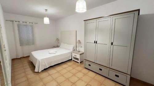 a bedroom with a white bed and a cabinet at Anahi Homes Corralejo- Bicacarera 7 in La Oliva