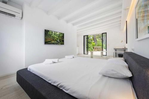 a white bedroom with a large bed and a couch at Can Verd Vall De Colonya in Pollença
