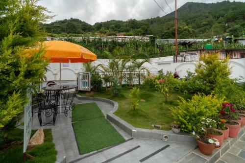 a patio with a table and an umbrella and plants at The White House Villa 8 bedroom with Swimming Pool in Kathmandu